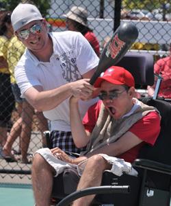 Man helping boy in wheelchair to bat